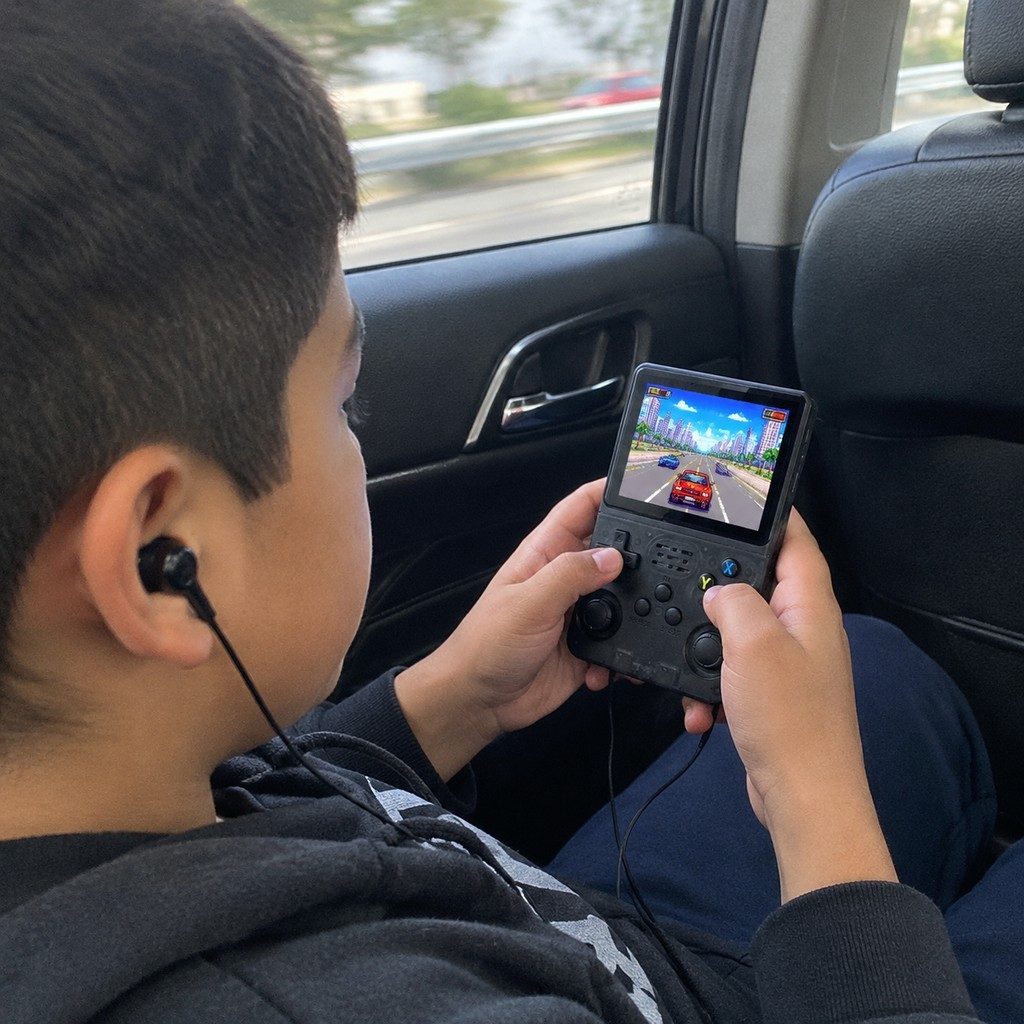 Boy playing Black console with headphones in a car